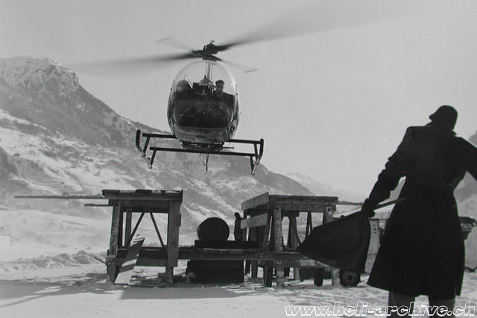 Foto 1 - Aerodromo di Ambrì febbraio 1955 - Sotto lo sguardo vigile del meccanico Jean Seydoux (girato di schiena) l'elicottero si appresta ad atterrare (HAB)