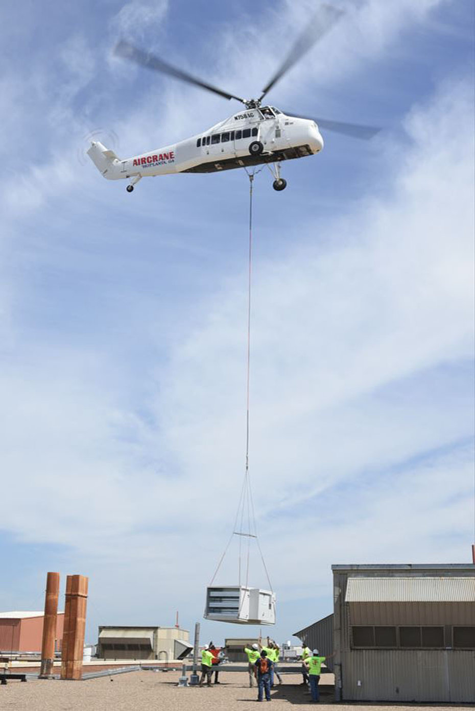 2018 - The Sikorsky S-58JT N758AC in service with Aircrane places an air conditioner onto the roof of a building (web)