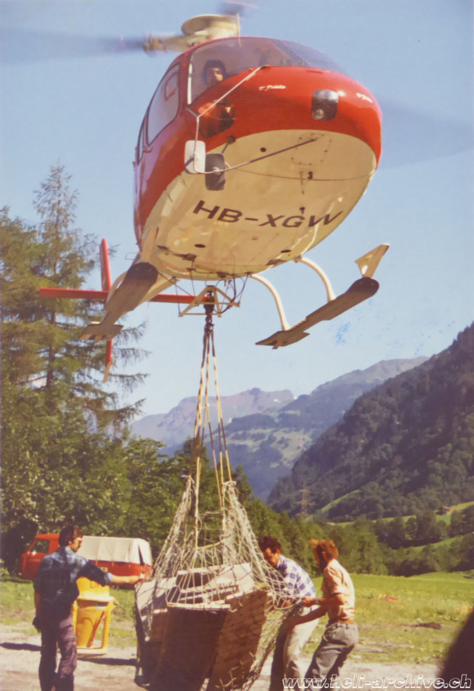 Glarus Alps, early 1980s - The AS 350B Ecureuil HB-XGW piloted by Peter Kolesnik transports a net of building material (family Kolesnik)